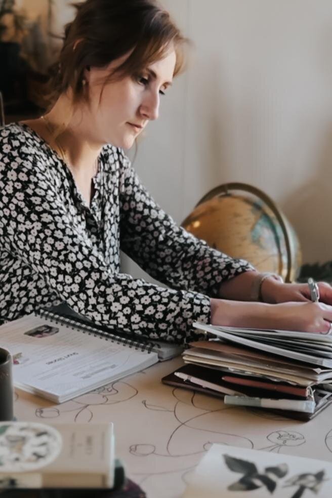 A woman writing in a planner at a desk with a globe nearby