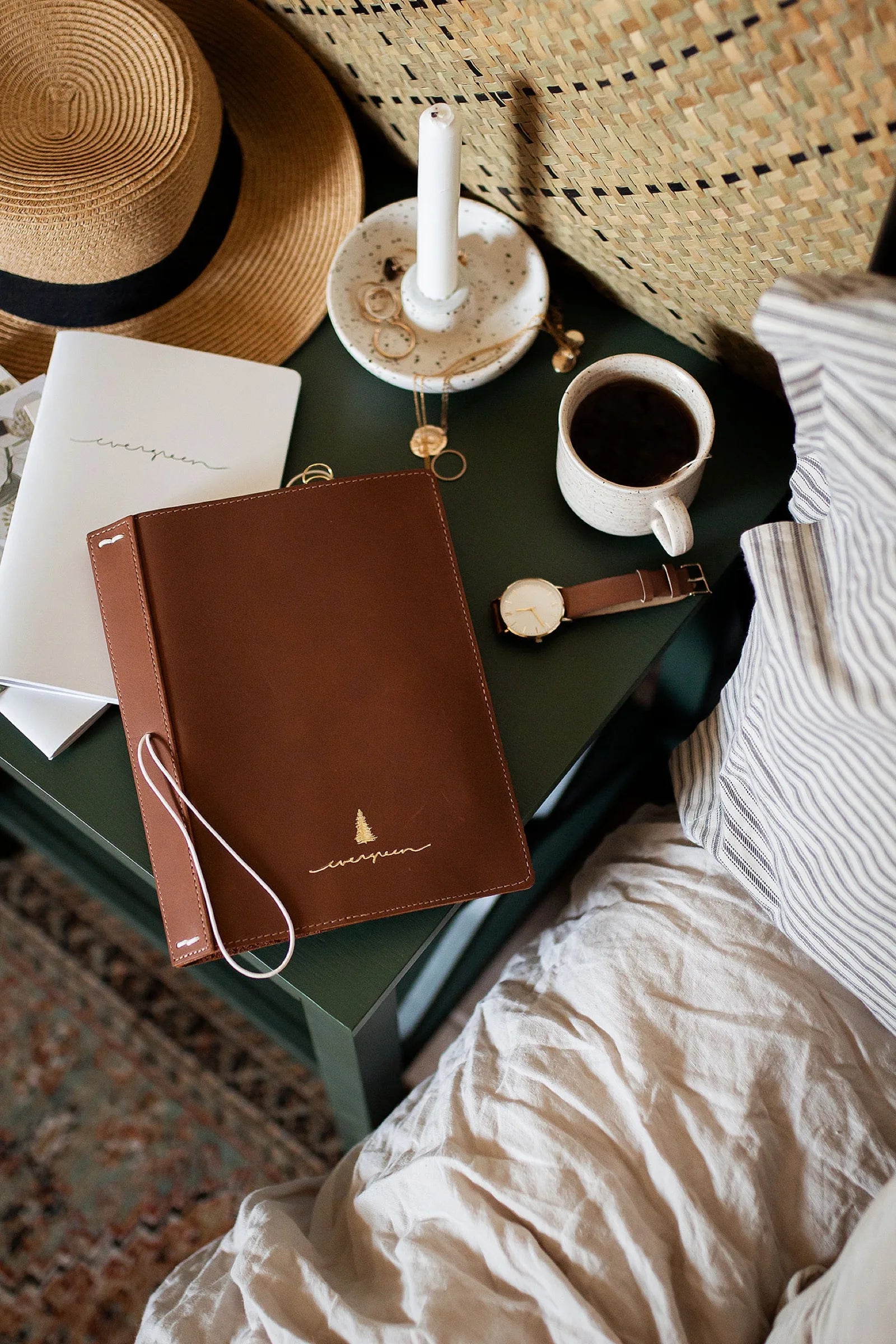 The planner closed on a bedside table beside coffee, a watch, and jewelry