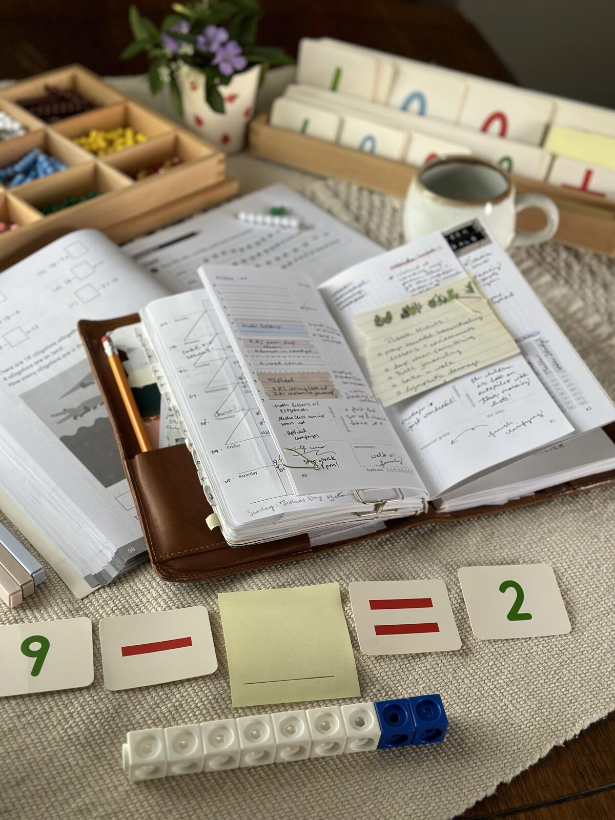 A planner open beside homeschool teaching materials on a desk