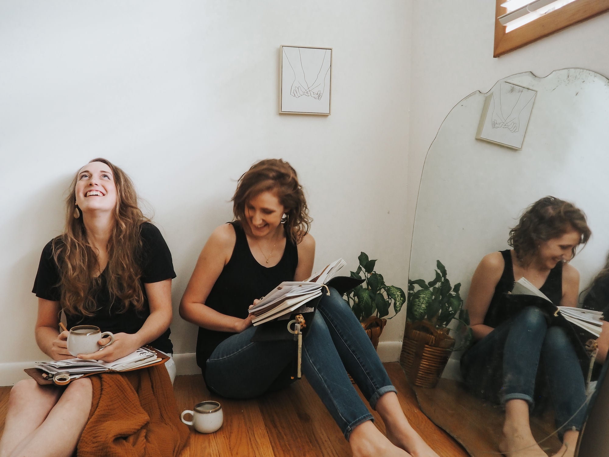 The Evergreen founders sitting on the floor together, planners open and coffee in hand.